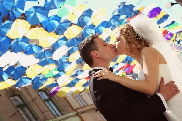 Bride and groom under colorful umbrellas — Stock Photo, Image