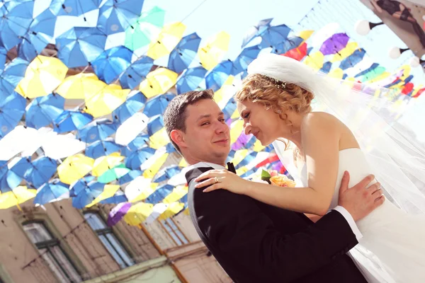 Bride and groom under colorful umbrellas — Stock Photo, Image