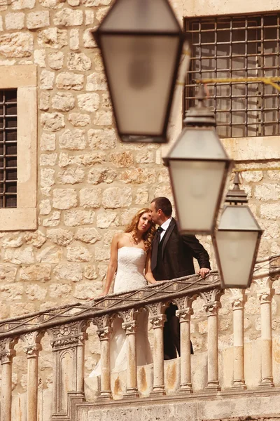 Bride and groom kissing on stairs in old city — Stock Photo, Image