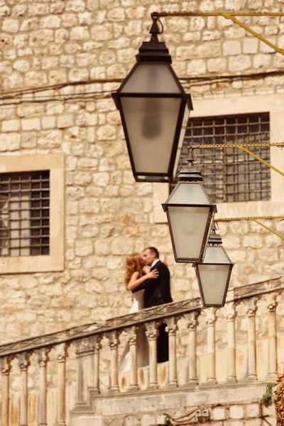 Bride and groom kissing on stairs in old city — Stock Photo, Image