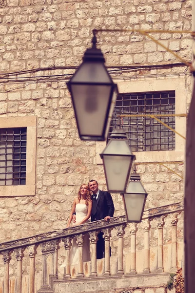 Bride and groom kissing on stairs in old city — Stock Photo, Image