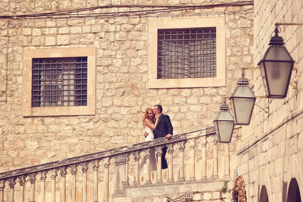 Bride and groom kissing on stairs in old city — Stock Photo, Image