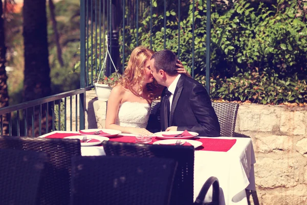 Noiva e noivo beijando na mesa do terraço — Fotografia de Stock