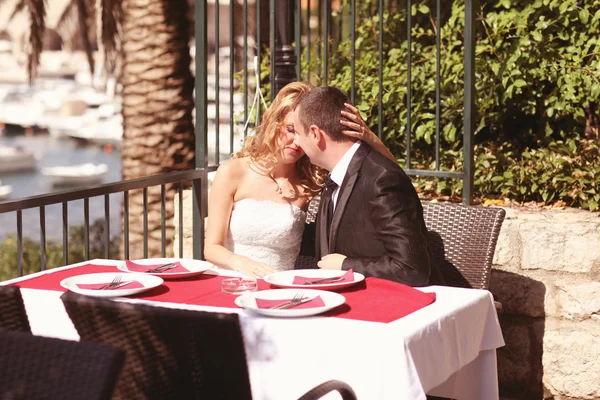 Noiva e noivo beijando na mesa do terraço — Fotografia de Stock