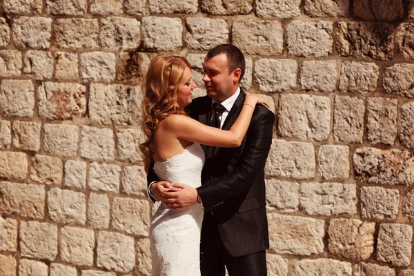 Bride and groom holding each other near old bricks — Stock Photo, Image