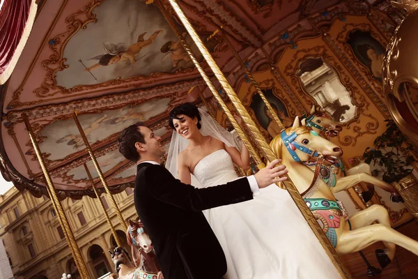 Gelukkige bruid en bruidegom op carrousel — Stockfoto