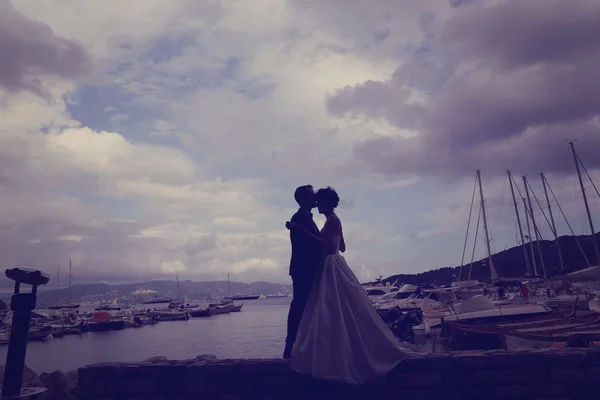Bride and groom in harbour with boats in background — Stock Photo, Image