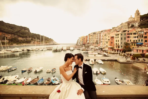 Bride and groom on bridge with boats in background — Stock Photo, Image