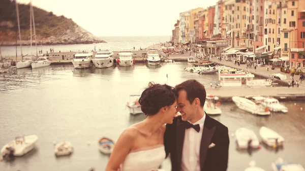 Bride and groom on bridge with boats in background — Stock Photo, Image