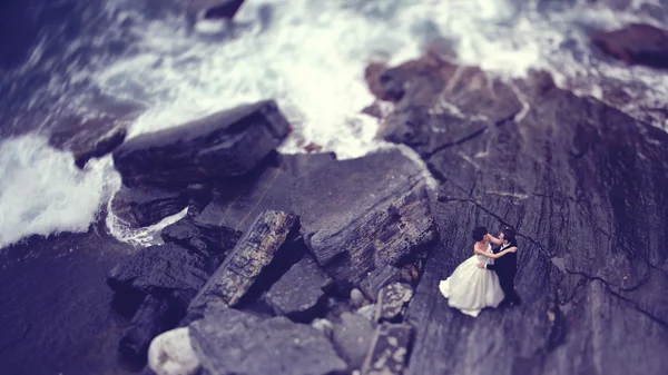 Bruden och brudgummen på klippa nära bryta vågor — Stockfoto
