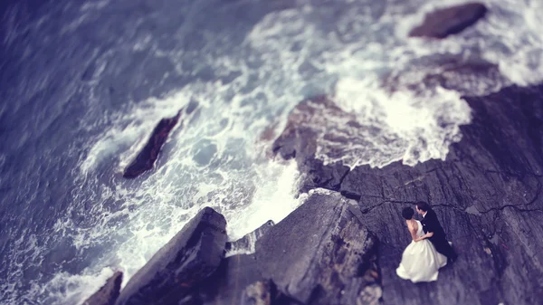 Nevěsta a ženich na skále poblíž prolomit vlny — Stock fotografie
