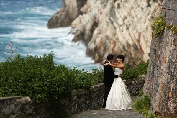 Bride and groom holding each other near seaside — Stock Photo, Image