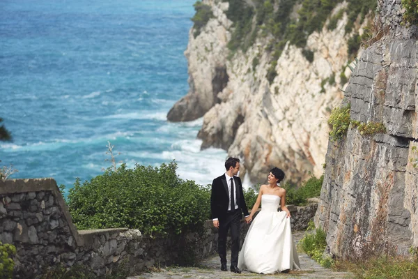Braut und Bräutigam halten Händchen am Meer — Stockfoto