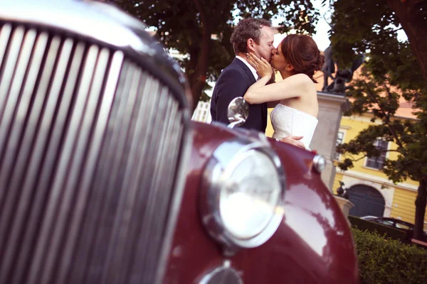 Menyasszony és a vőlegény szórakozás retro autó közelében — Stock Fotó