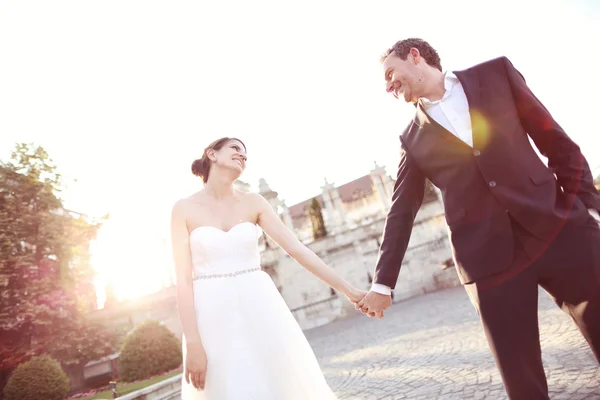 Bride and groom holding hands in the sunlight — Stock Photo, Image