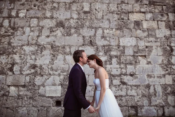 Bruid en bruidegom kussen in de buurt van bakstenen muur — Stockfoto