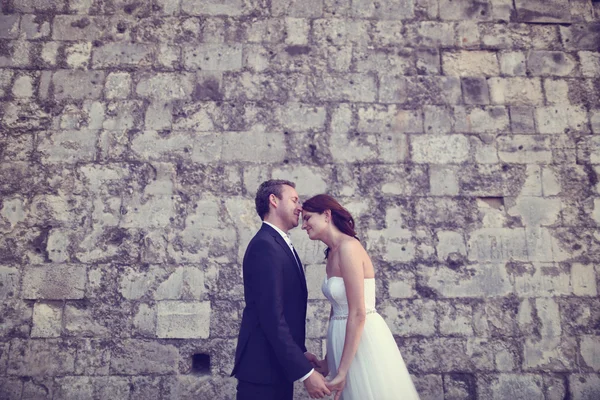 Sposa e sposo baciare vicino muro di mattoni — Foto Stock