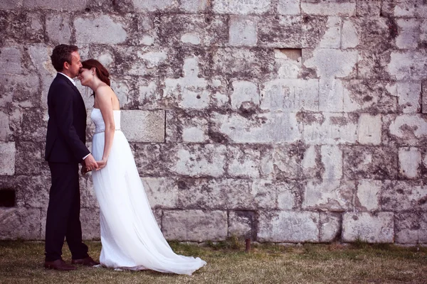 Gelin ve damat öpüşme tuğla duvara yakın — Stok fotoğraf