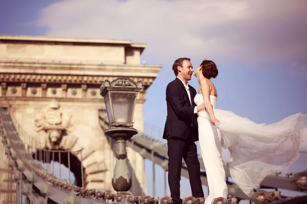 Жених и невеста веселятся на мосту — стоковое фото