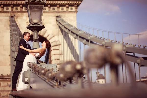 Bride and groom having fun on a bridge — Stock Photo, Image