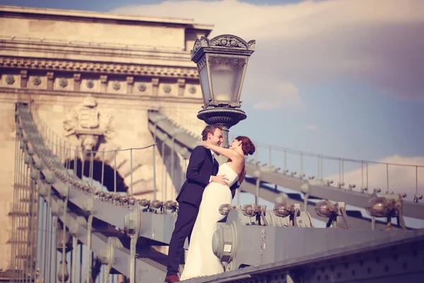 Bride and groom having fun on a bridge — Stock Photo, Image