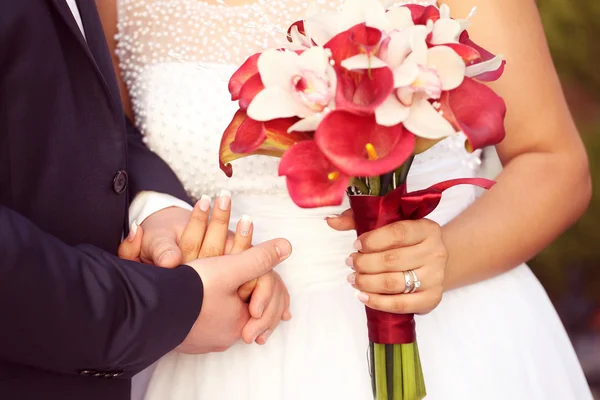 신부 및 신랑의 손입니다. 신부 지주 붉은 백합 꽃다발 — 스톡 사진