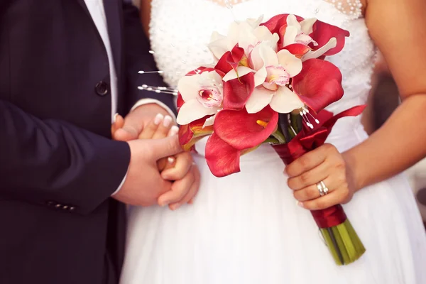 Руки нареченого і нареченого. Наречена тримає букет червоної лілії — стокове фото