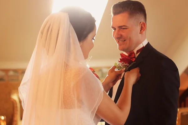 Braut legt ihrem Bräutigam Blumen auf die Brust — Stockfoto