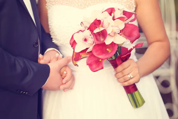 Hands of a bride and groom. Bride holding red lily bouquet Royalty Free Stock Images