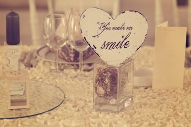 You make me smile. Heart shaped card on wedding table clipart