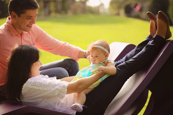 Aanhankelijk ouders met hun babymeisje in het park — Stockfoto
