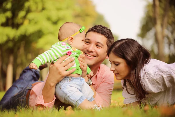 Pais com bebê menina sentada na grama no parque — Fotografia de Stock