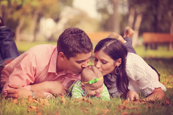 Ouders met babymeisje, zittend op het gras in het park — Stockfoto