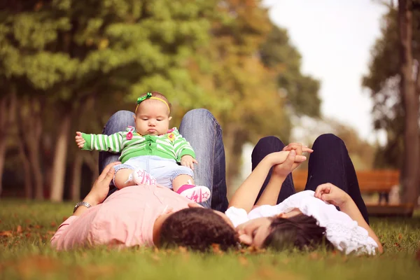 Os pais se deitam segurando sua menina — Fotografia de Stock