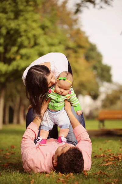 Pais deitar segurando seu bebê menina para cima — Fotografia de Stock