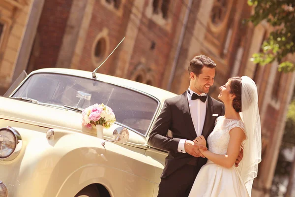 Novia y novio con un coche retro — Foto de Stock