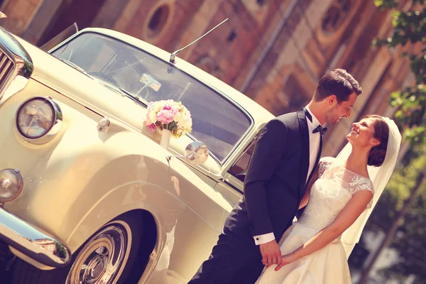 Bruden och brudgummen med en retro bil — Stockfoto