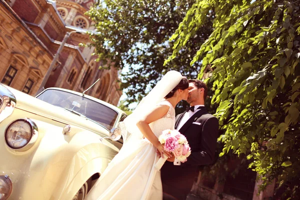 Bride and groom with a retro car — Stock Photo, Image