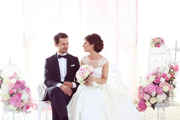 Bride and groom surrounded by flowers — Stock Photo, Image