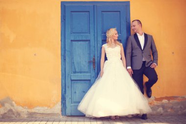 Gelin ve damat sarı duvar ve mavi kapı karşı