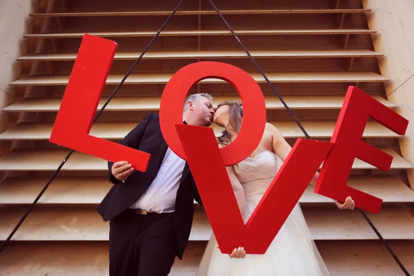 Sposa e sposo in possesso di grandi lettere d'amore rosso — Foto Stock