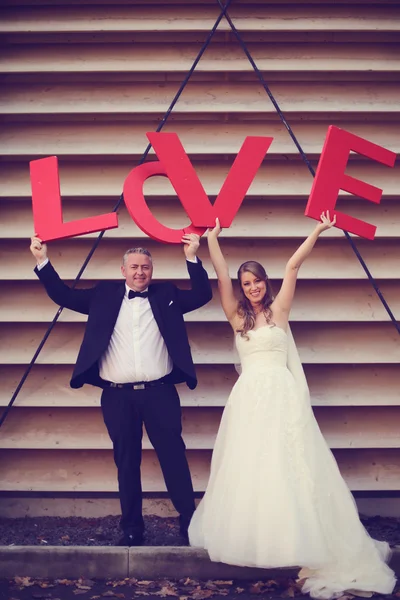 Braut und Bräutigam mit großen roten Liebesbriefen — Stockfoto