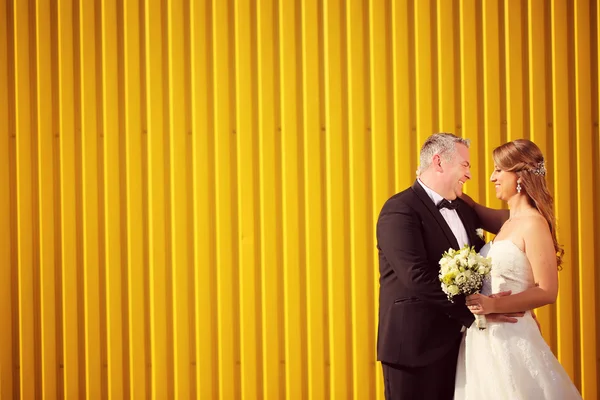 Bruid en bruidegom in de buurt van geel muur — Stockfoto