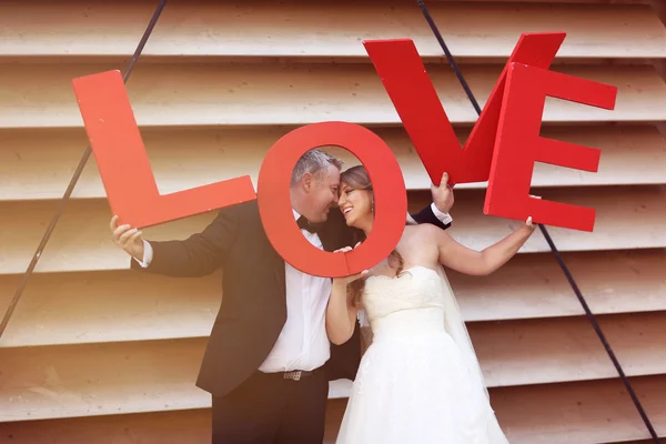 Novia y novio sosteniendo grandes letras rojas de AMOR — Foto de Stock