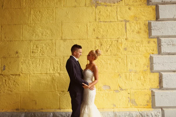 Mariée et marié face à un mur jaune — Photo