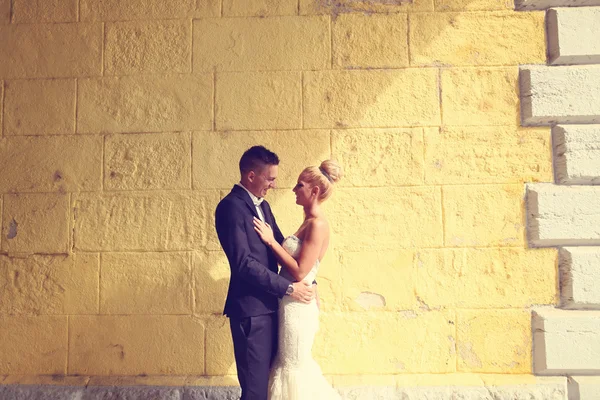 Жених и невеста смотрят на желтую стену — стоковое фото