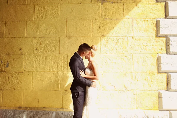 Novia y novio frente a una pared amarilla —  Fotos de Stock