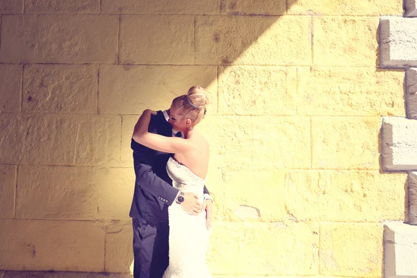 Mariée et marié face à un mur jaune — Photo