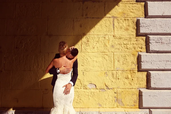 Mariée et marié face à un mur jaune — Photo