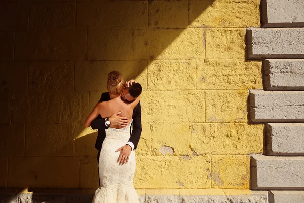 Sposa e sposo di fronte a un muro giallo — Foto Stock